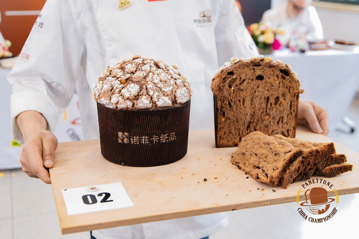 two panettone being presented inside novacart baking molds on a wooden surface